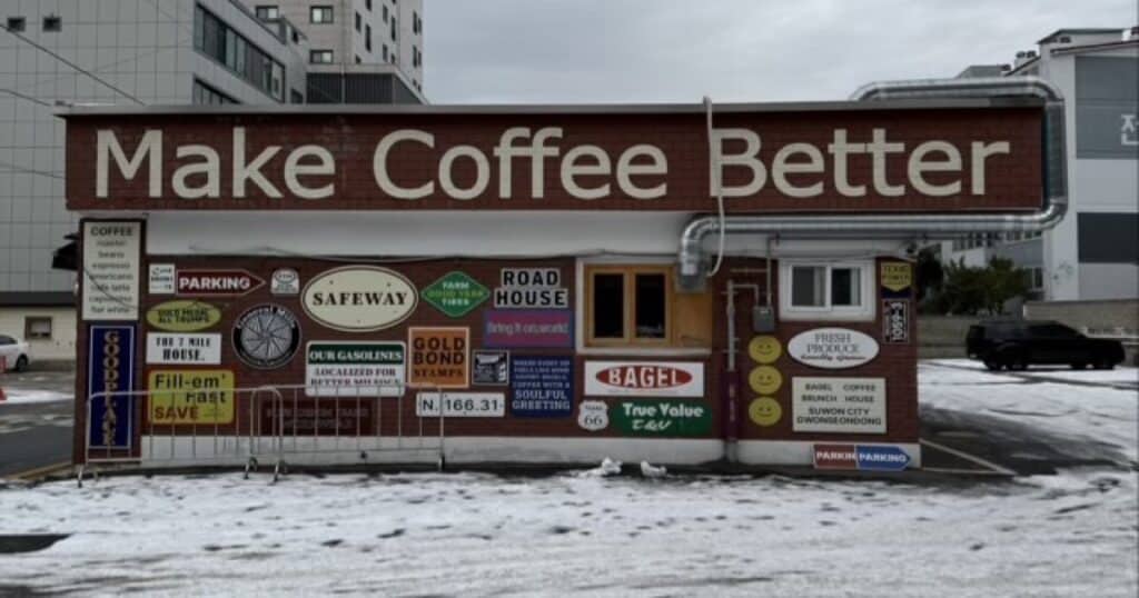 눈 덮인 주차장 앞에 위치한 수원 권선동 1059-3 베이글 커피하우스의 그래피티와 빈티지 간판으로 장식