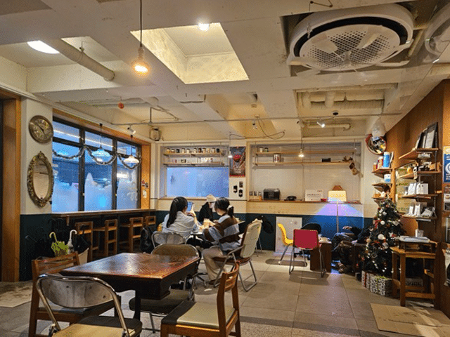 칠복상회로스터스 넓은 실내 좌석: 다양한 의자와 창가 바 테이블, 천장의 노출 배관과 보