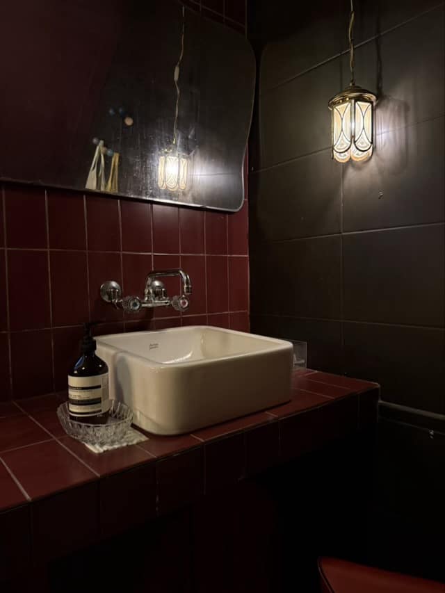 어두운 무드의 욕실 공간에 은은하게 빛나는 스테인드글라스 스타일의 벽부등 조명