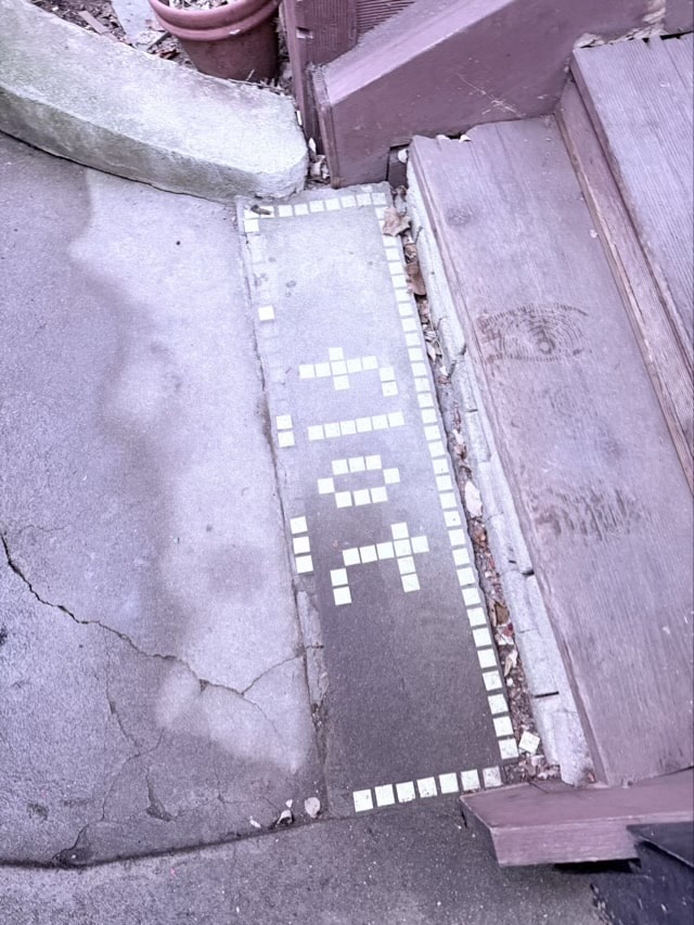 카페 입구 바닥에 'FLOT' 문구가 화이트 모자이크 타일로 새겨진 빈티지한 입구 모습