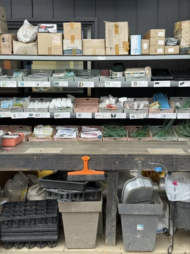 원예 용품, 모종판, 작은 화분, 비닐끈, 삽 등 다양한 원예 도구와 재료가 정리된 선반