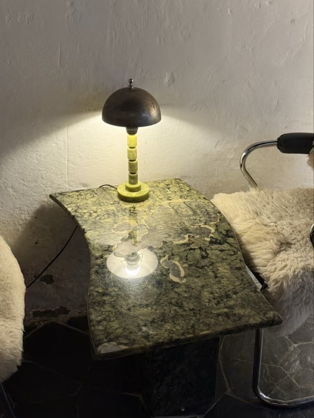 고급스러운 초록색 대리석 테이블 위에 놓인 황동 돔 형태의 빈티지 단스탠드