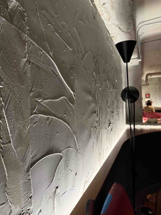 플라스터 미장 텍스쳐와 간접 조명이 조화된 카페 인테리어 벽면