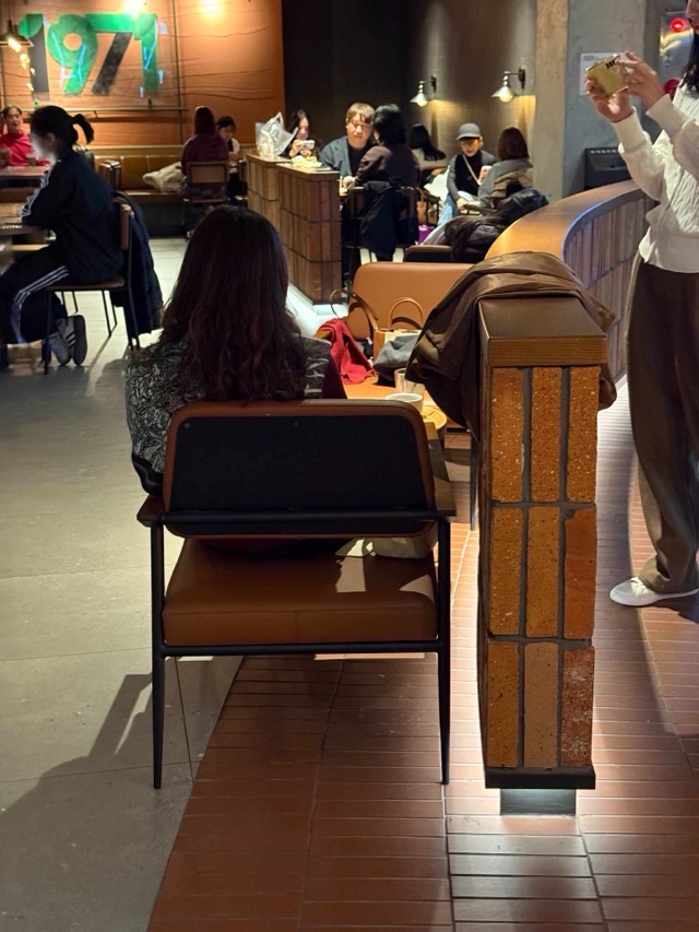 적벽돌 벽과 브라운 톤 의자가 있는 따뜻한 분위기의 카페 공간