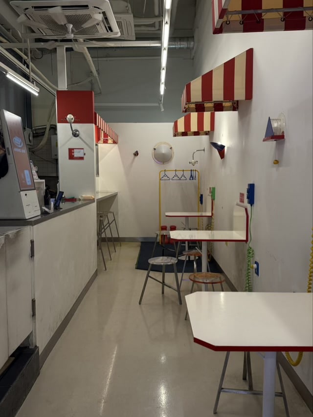 마곡 어닝바 내부 전경. 긴 복도식 공간에 배치된 오픈 키친과 테이블 (상업시설 인테리어)