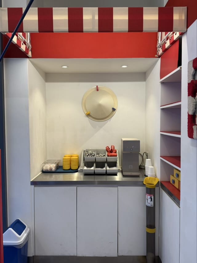 빨강/흰색 어닝 아래에 위치한 마곡 어닝바의 셀프 바 공간 및 원색 소품 배치