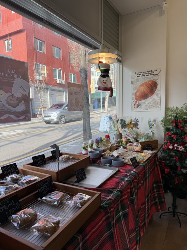 창가 조명 아래 배치된 성신여대 마피의 빵 진열대와 체크 패브릭