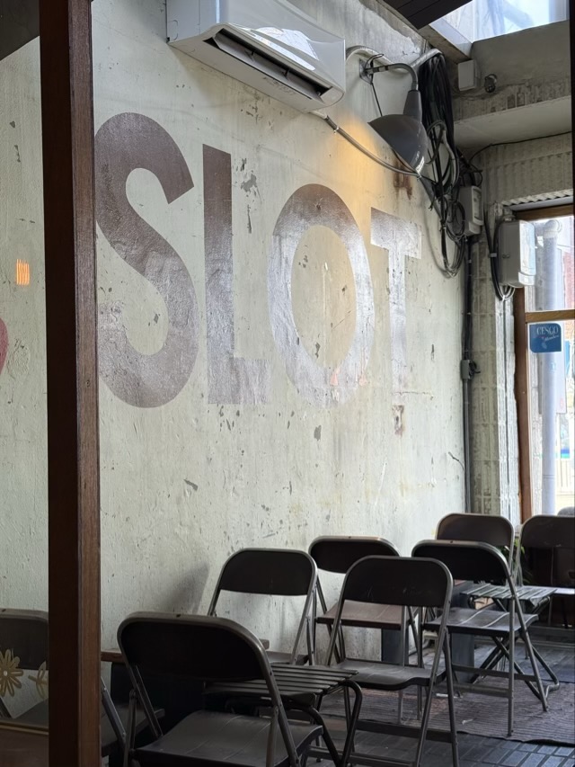 화이트 빈티지 벽면에 'SLOT' 타이포그래피가 새겨진 감각적인 벽면