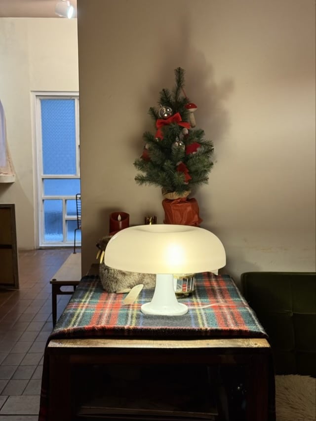 체크무늬 천이 깔린 테이블 위 버섯 모양의 화이트 조명과 작은 크리스마스 트리