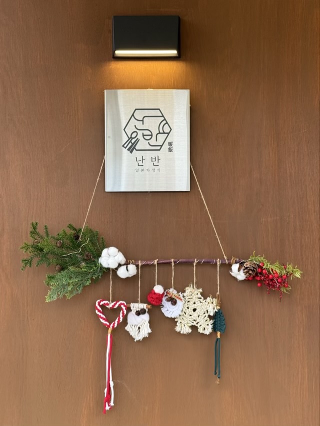 난반 로고 아래 걸린 목화솜과 솔방울 크리스마스 시즌 장식