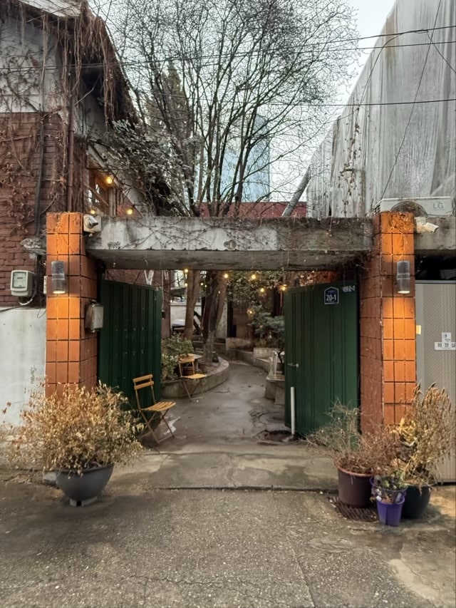 은평카페 flot의 녹색 프레임 중문과 철평석 바닥, 박공지붕 별 조명이 어우러진 은평플로 내부 전경