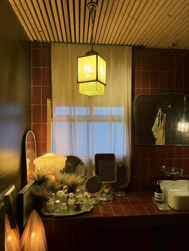 붉은색 타일이 인상적인 세면대 공간과 노란색 프릴 장식의 빈티지 펜던트 조명