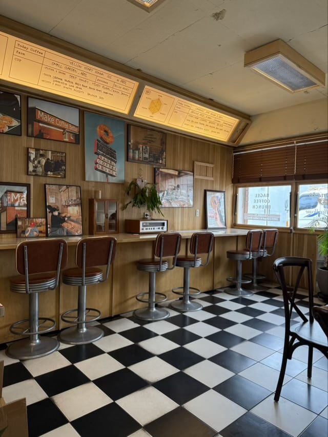 1059-3 베이글 커피하우스 내부의 레트로 다이너 스타일 좌석, 우드 패널 벽면과 체크무늬 바둑이 타일 바닥.