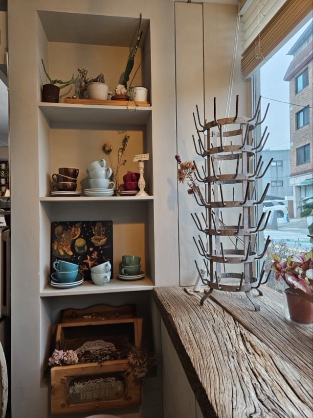 매립형 선반과 아기자기한 컵, 소품으로 꾸며진 성북동 카페 케이드 벽면