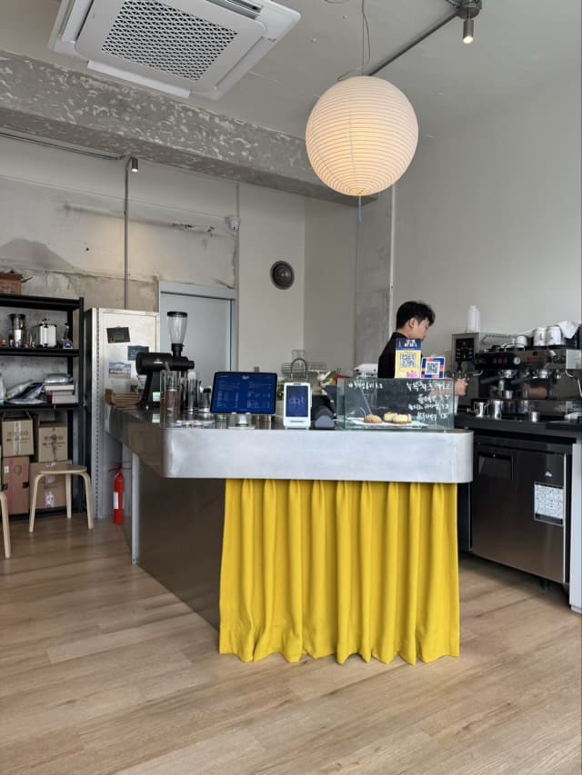 노란색 커튼 포인트가 돋보이는 dprt 카페의 스테인리스 카운터